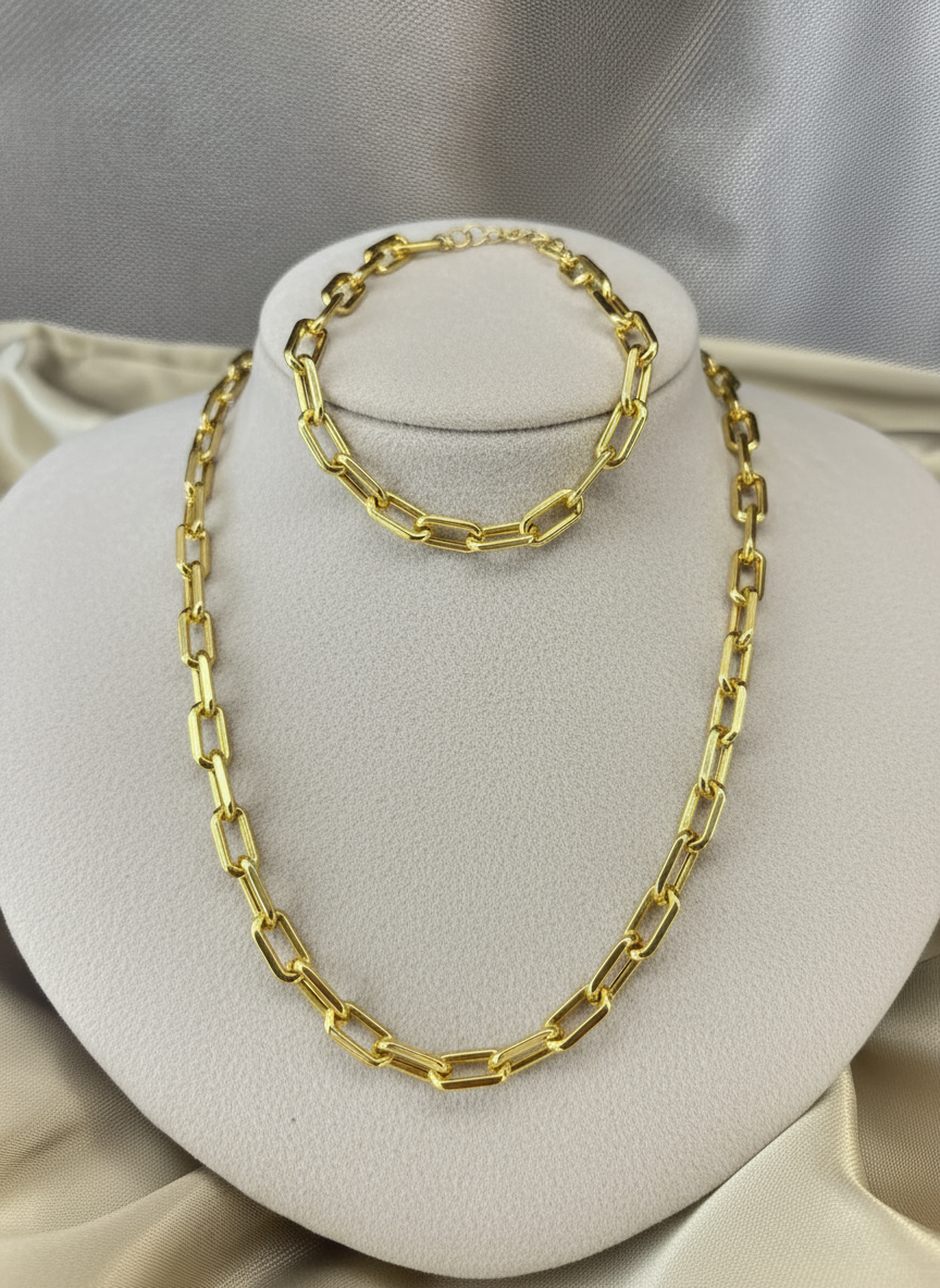 Gold paperclip necklace and bracelet on ivory display