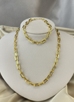 Gold paperclip necklace and bracelet on ivory display