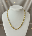 Gold paperclip necklace on ivory display